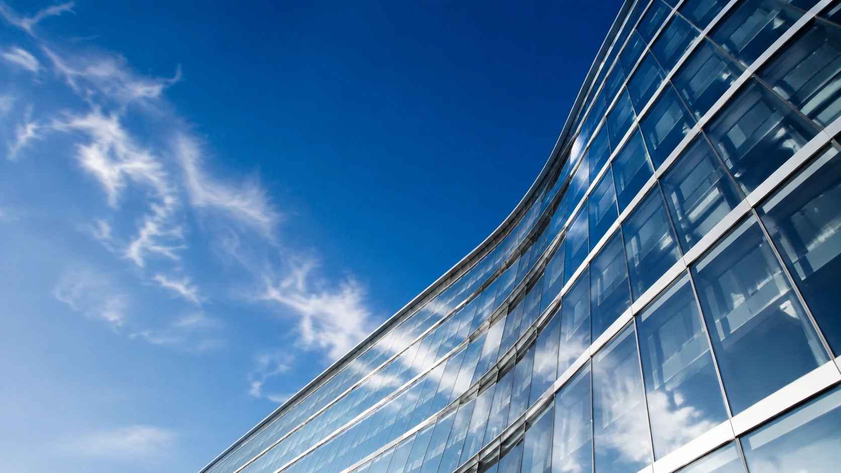 Perspectiva de una fachada de cristal bajo un cielo azul